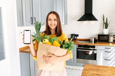 Frau hat gesunde Lebensmittel eingekauft und nutzt eine Ernährungsapp