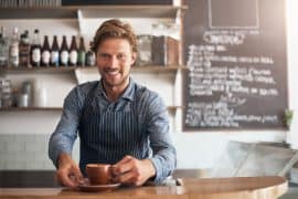 Barista mit einer Tasse Kaffee und mit einer Schürze an