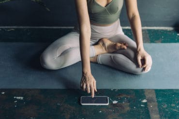 Frau sitzt auf einer Yogamatte